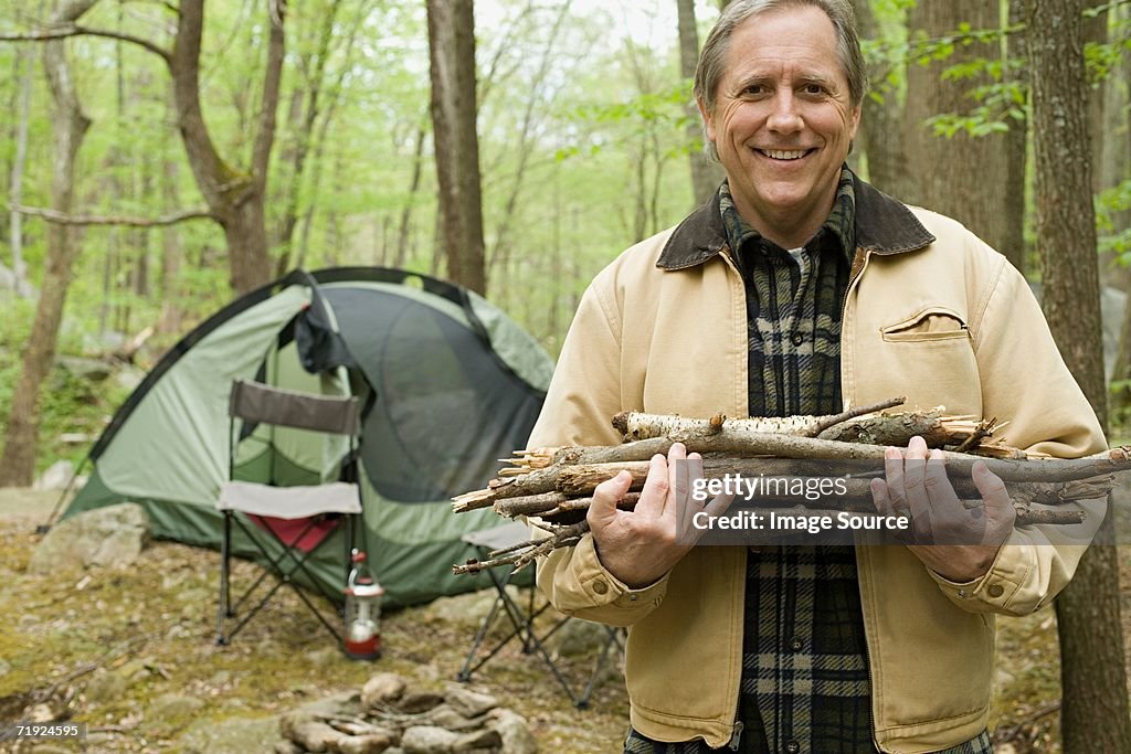 Mature man carrying logs in a forest