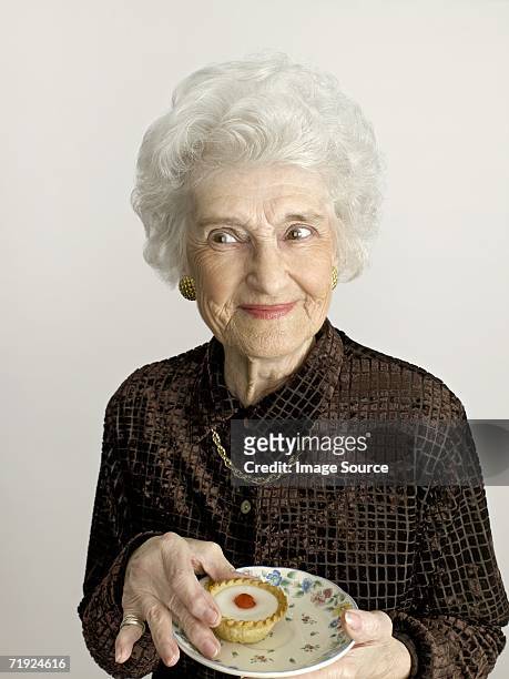 senior woman with cherry bakewell tart - sonrisa satisfecha fotografías e imágenes de stock