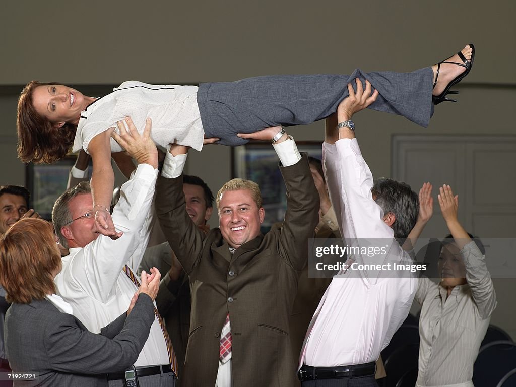 Office workers lifting colleague up