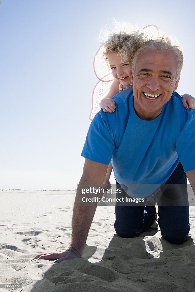 Grandfather playing with granddaughter on beach