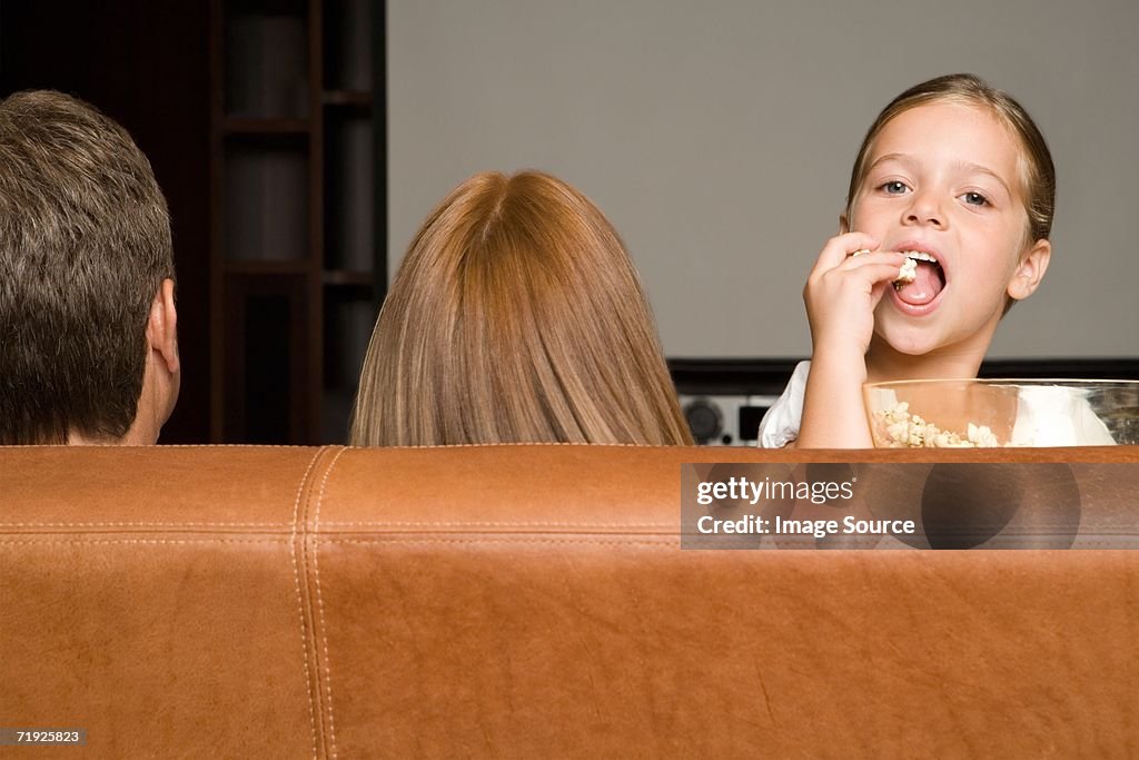 Girl eating popcorn with family