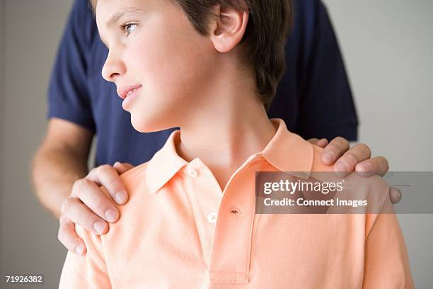 boy with father's hand on shoulders - hand shoulder stock pictures, royalty-free photos & images
