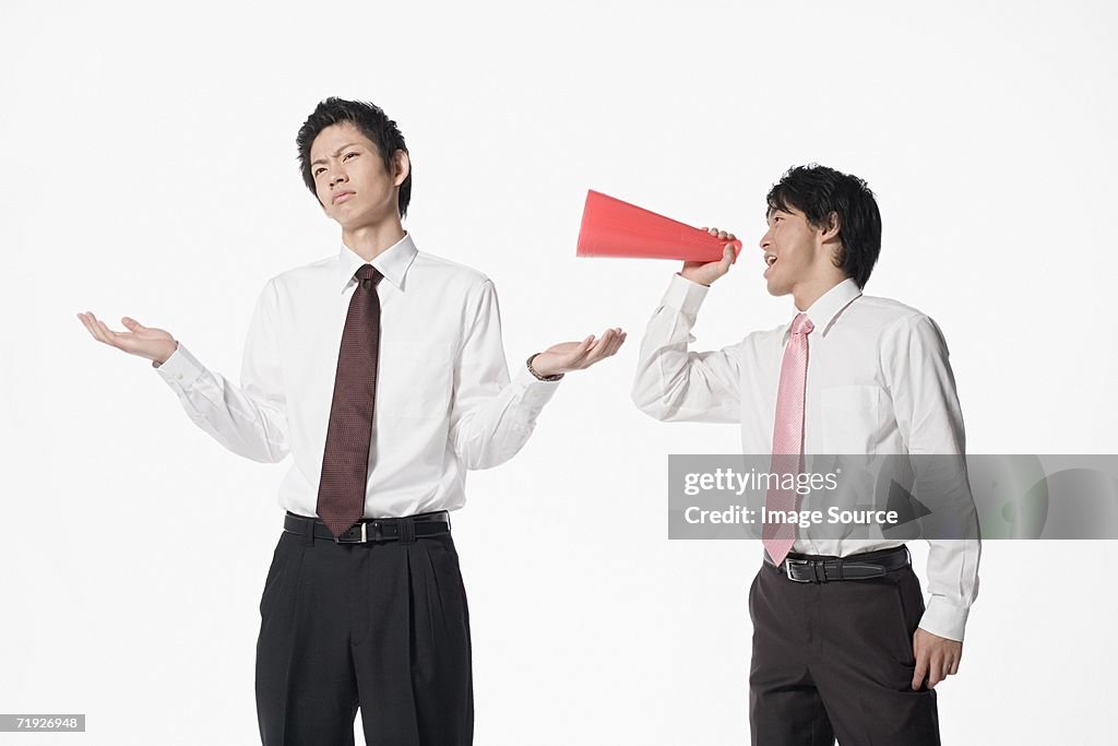Man shouting at colleague with megaphone