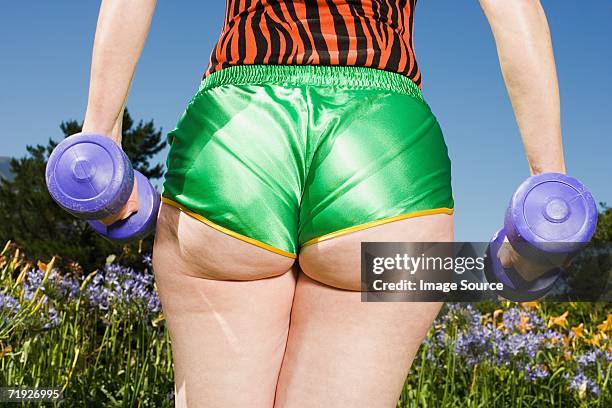 senior adult woman wearing hotpants lifting dumbbells - rear end bildbanksfoton och bilder