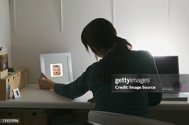 woman looking at picture of baby - picture frame desk stock pictures, royalty-free photos & images