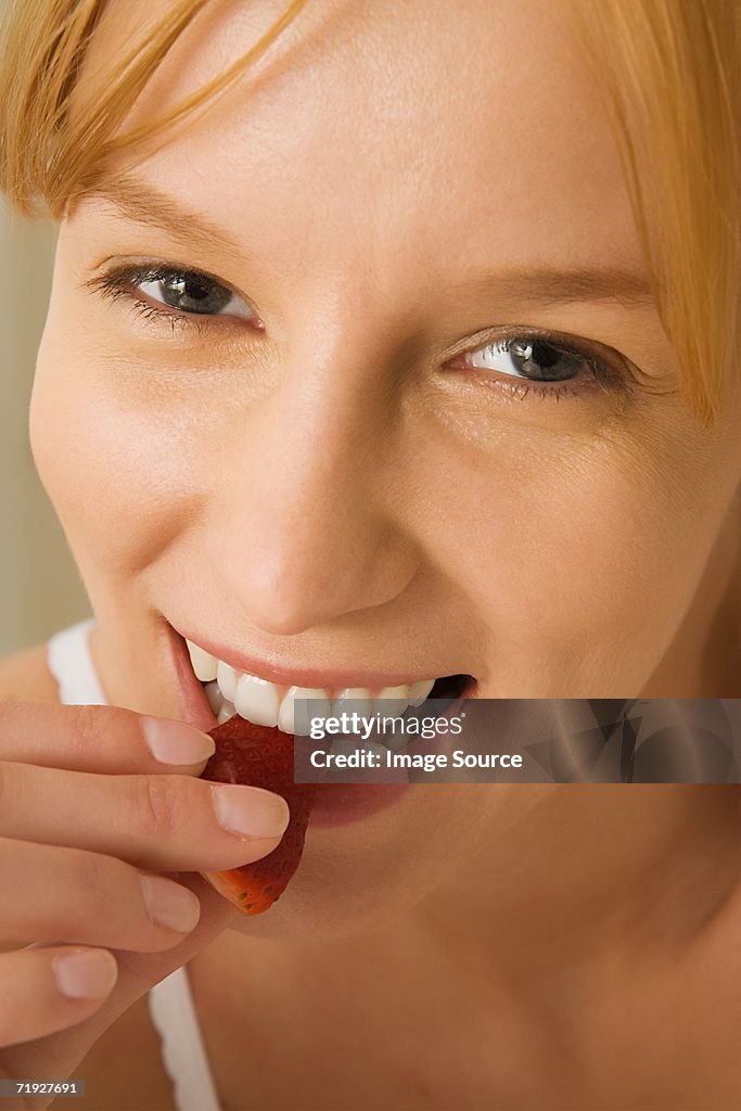 Woman eating slice of strawberry