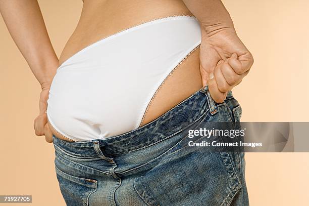 woman putting on jeans - aankleden stockfoto's en -beelden