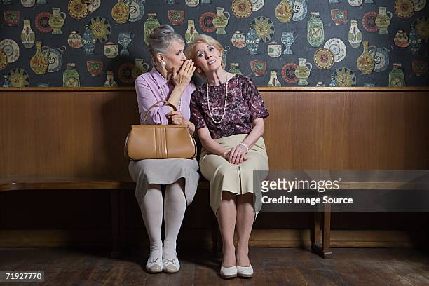 senior woman whispering to friend - chuchoter photos et images de collection