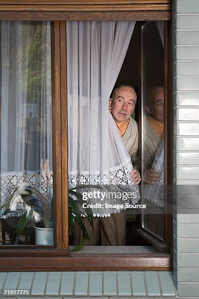 senior peering around net curtain - window curtains stock pictures, royalty-free photos & images