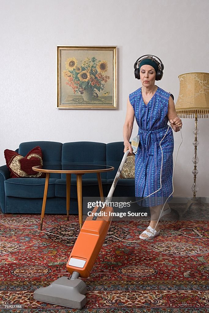 Woman wearing headphones and vacuuming