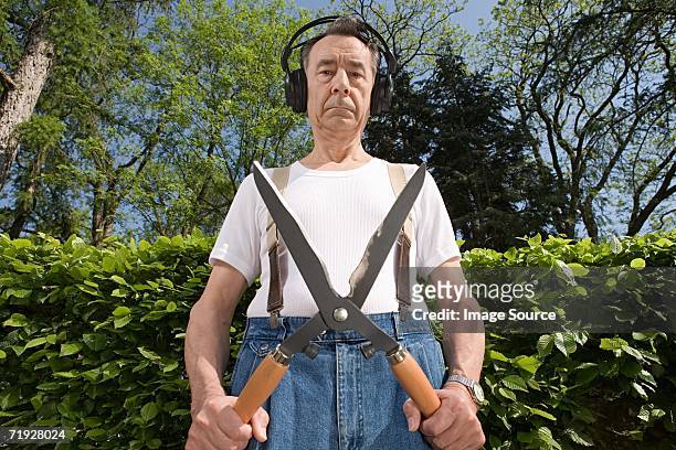 man wearing headphones and holding gardening shears - threats stockfoto's en -beelden