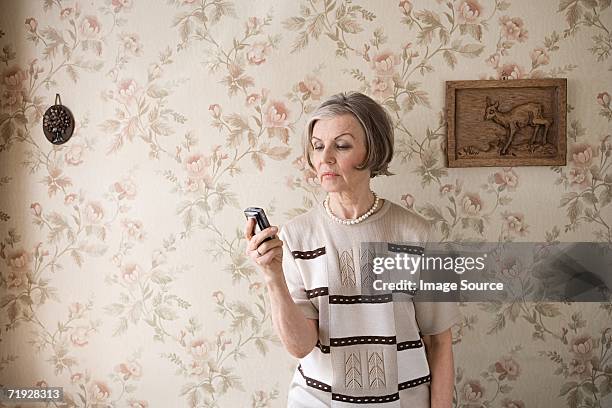 senior woman with cell phone - froncer les sourcils photos et images de collection