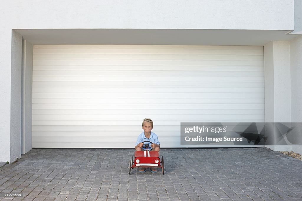 Young boy sat in a toy car