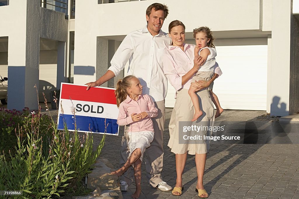 Family stood outside house holding sold sign