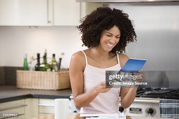 smiling woman reading a brochure in kitchen - direct mail stockfoto's en -beelden