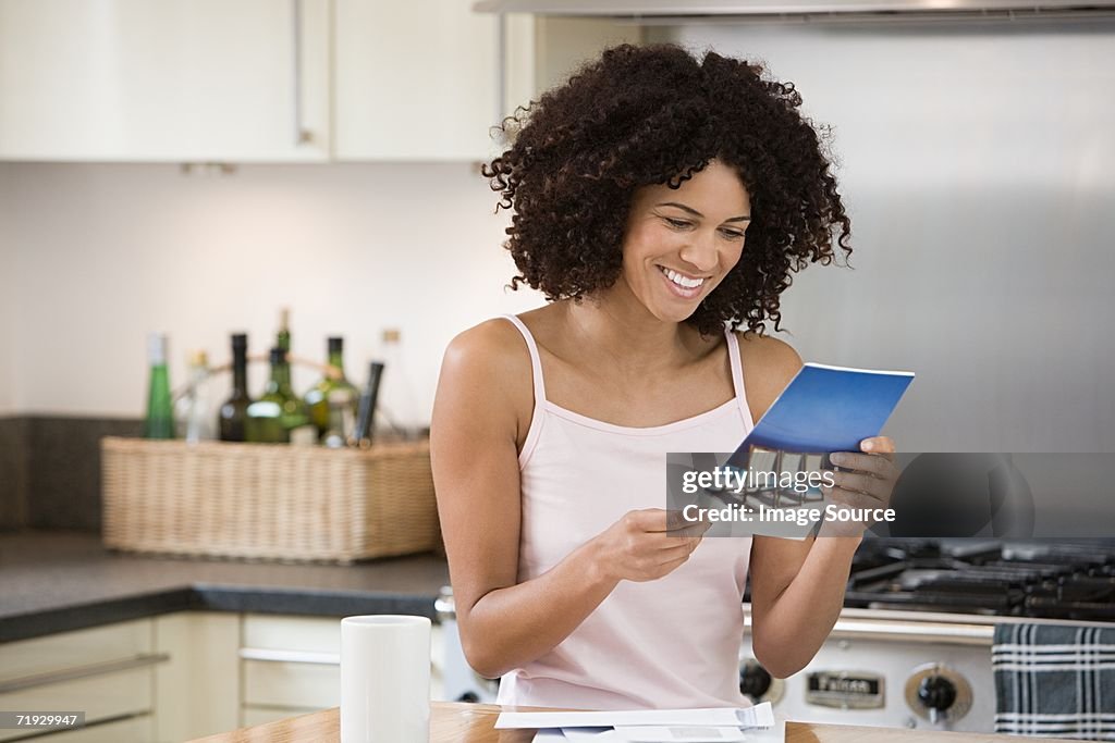 Smiling woman reading a brochure in kitchen