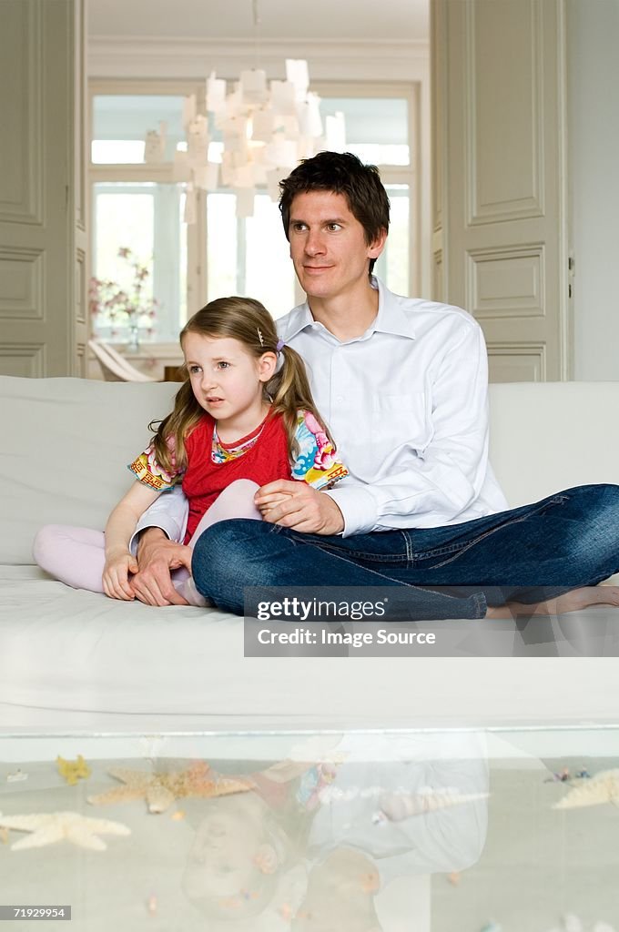 Father and daughter sat on sofa