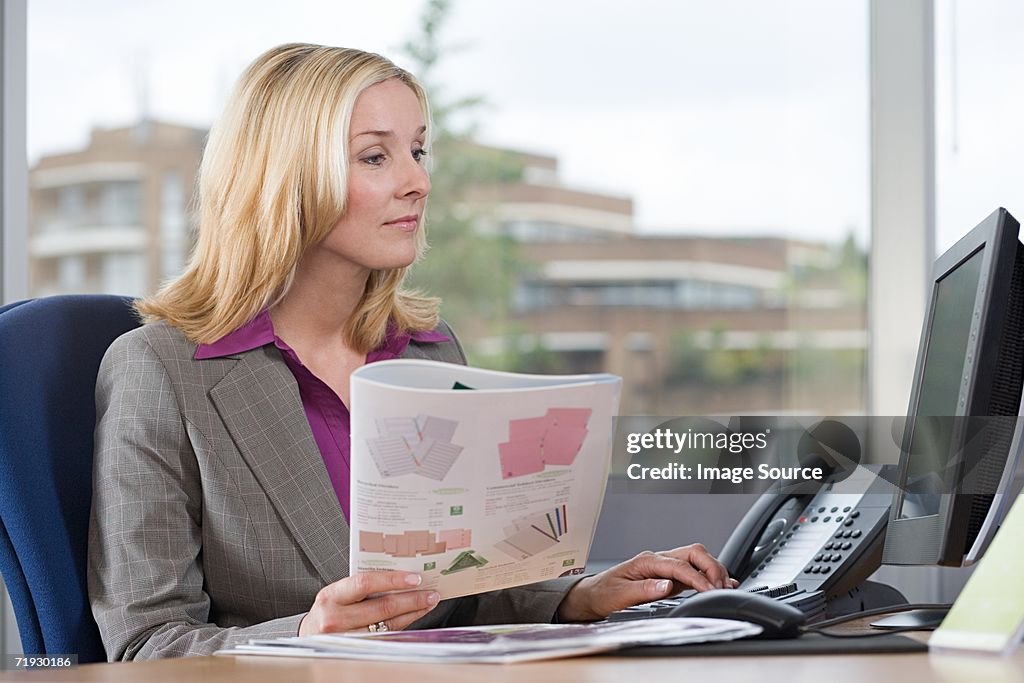 Businesswoman holding a brochure at desk