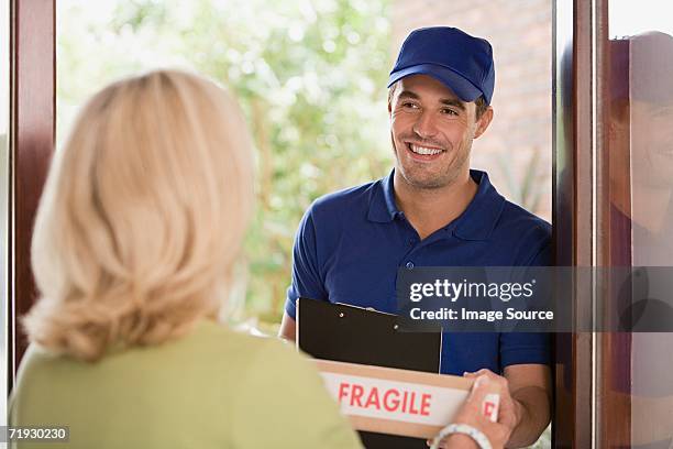 woman getting a parcel from delivery man - answering door stock pictures, royalty-free photos & images