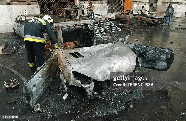 Hungarian firefighters examine 19 September 2006 the wrecks of burnt cars in front of the Hungarian national television headquarters after the...