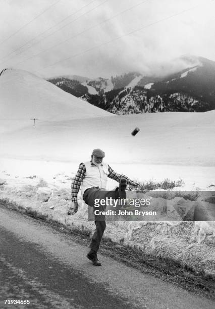 American author and journalist Ernest Hemingway drop kicks a can as he walks along a road, near Ketchum, Idaho, winter of 1960-61. The Boulder...