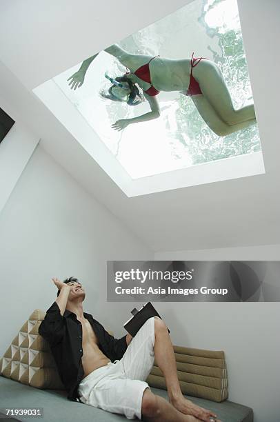 man waving at woman in swimming pool through the skylight - bermuda snorkel stock pictures, royalty-free photos & images