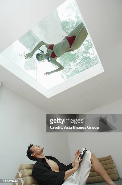 man looking at woman in swimming pool through the skylight - bermuda snorkel stock pictures, royalty-free photos & images
