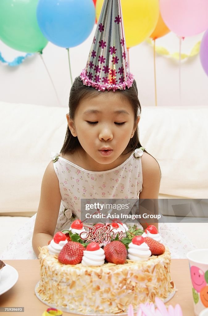Girl blowing out candle on a cake