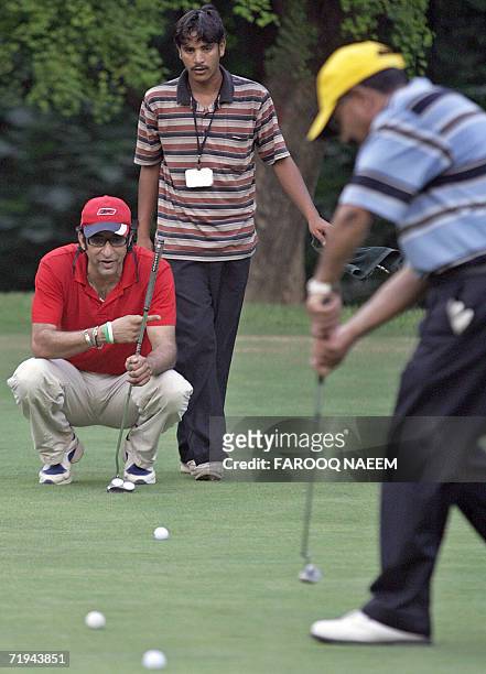 In this picture taken 19 September 2006, former Pakistani cricketer Wasim Akram watches Golf club Secretary Shahab Hashmi play his final shot during...