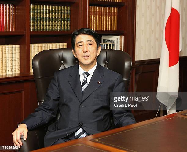 Newly elected Japanese ruling Liberal Democratic Party President Shinzo Abe smiles as he settles into the presidential seat at the LDP headquarters...