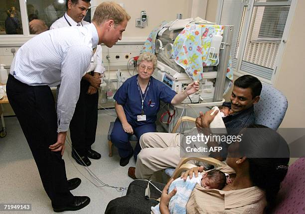 Britain's Prince William speaks to father Bobby Sebastian and mother Marykutty Thomas holding their new babies Noel and Joel, in the Winnicott Baby...