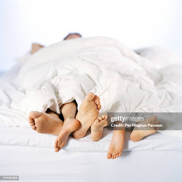 bare feet sticking out under a blanket. - mens bare feet fotografías e imágenes de stock