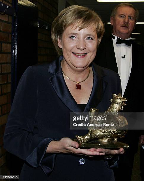 German Chancellor Angela Merkel smiles with the "Goldene Henne" trophy at the Friedrichstadtpalast on September 20, 2006 in Berlin, Germany. Merkel...