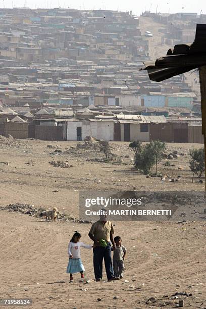 Un padre con sus hijos camina en el asentamiento de Lomo de Corvina en Lima el 02 de junio de 2006. Durante los ultimos cuatro anos, la tasa de...
