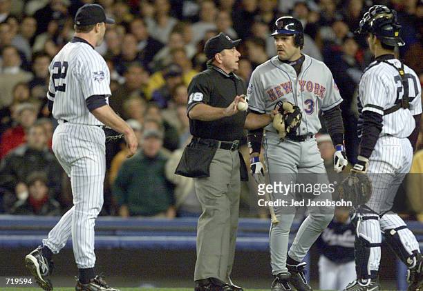 Mike Piazza of the New York Mets is restrained by home plate umpire Charlie Reliford from pitcher Roger Clemens after Clemens threw his broken bat in...
