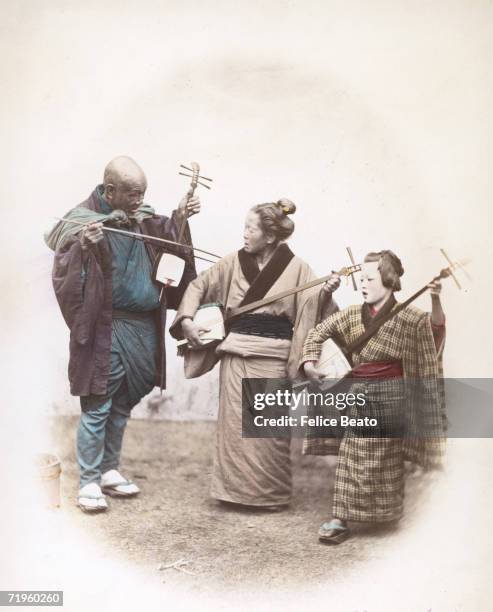 Three Japanese street musicians playing the shamisen, circa 1865.