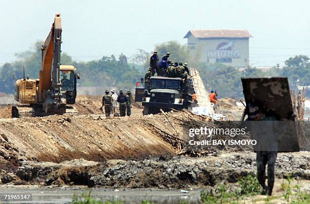 Villager carries a door as he walks next to a dyke that is being used to stop the mud that erupted from a Lapindo Brantas Inc. Gas exploration well...