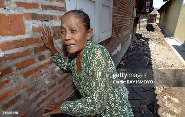 Villager stand close to the wall of her house which was flooded by gushing mud that erupted from a Lapindo Brantas Inc. Gas exploration well in...