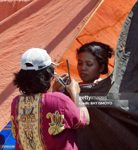 Villagers stitch together a tent on a toll road which they use as their temporary shelter from gushing mud that covered their village erupted from a...