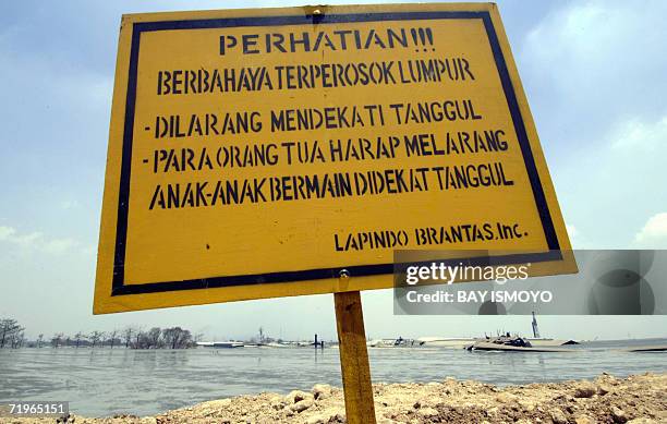 Warning sign stands next to the gushing out mud of a Lapindo Brantas Inc. Gas exploration well in Sidoarjo, East Java, 19 September 2006, which...