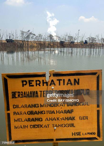 Warning sign stands next to a dyke which is attempting to stop the gushing mud erupting from a Lapindo Brantas Inc. Gas exploration well in Sidoarjo,...