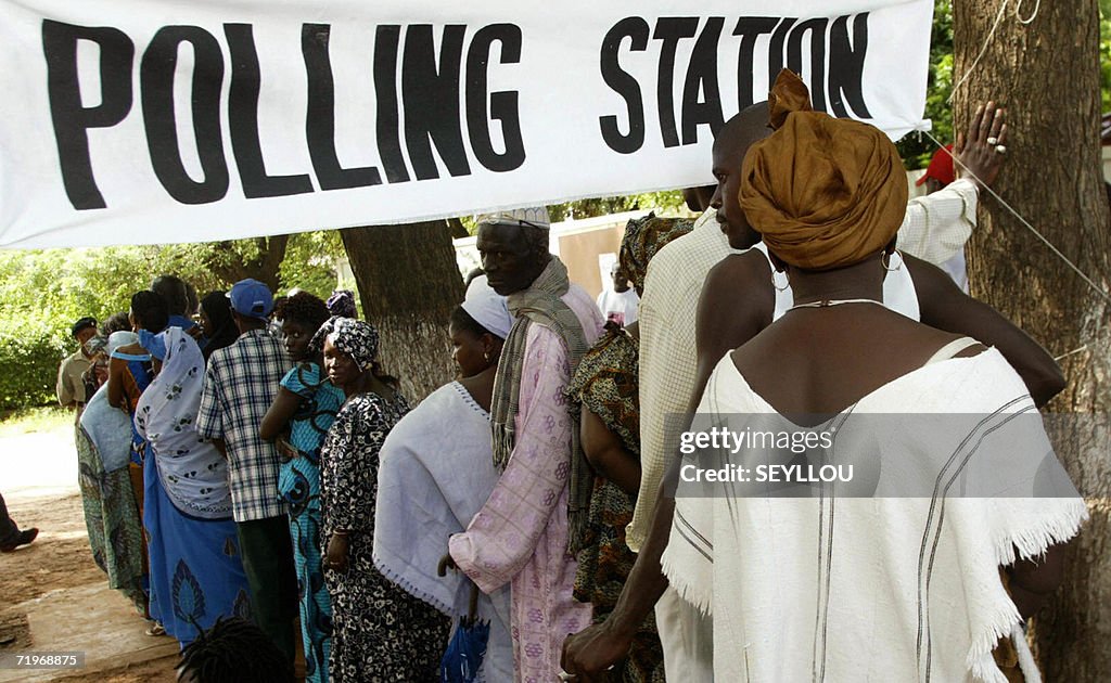 Gambians stand in line infront of a poll