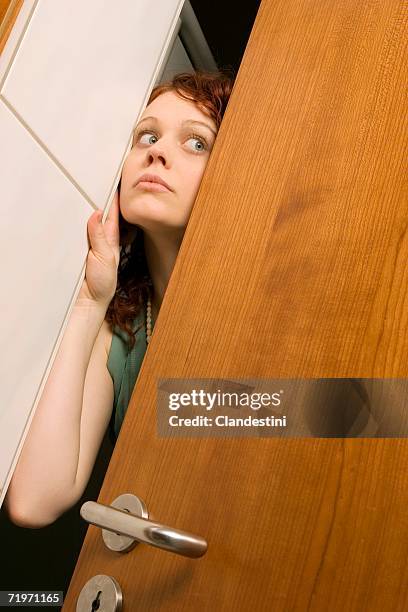 young woman peeking through door, close-up - suspicious stock pictures, royalty-free photos & images