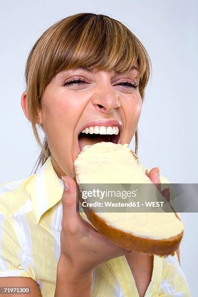 young woman eating bread and butter, close-up - brot mund stock-fotos und bilder