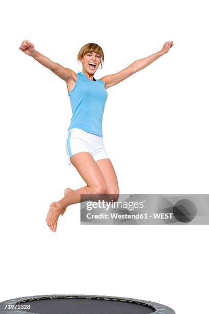 young woman jumping on trampoline, low angle view - trampoline jump stock-fotos und bilder