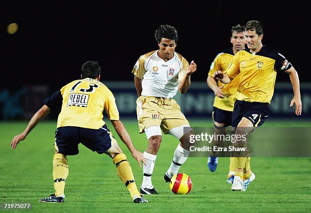 Noel Spencer and Tony Vidmar of the Central Coast Mariners try to defend against Nick Carle of the Newcastle Jets during the round five A-League...