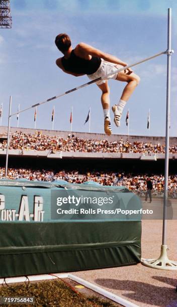 American high jumper Dick Fosbury uses the new 'Fosbury Flop' technique to clear the bar in competition to finish in first place to win the gold...