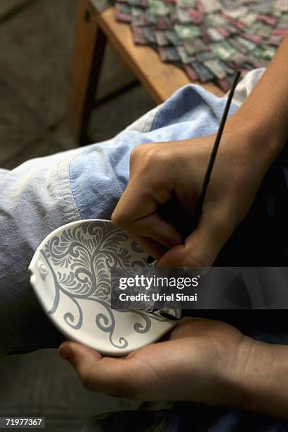 An Uzbek potter paints traditional patterns on a plate before it is glazed andf fired in a workshop, making the blue ceramics that the region is...