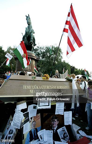 Protestors stand beside a mock coffin that reads "Temetjuk a Gyurcsany kormanyt! Nektek nincs feltamadas!" which translates to "Bury Prime Minister...