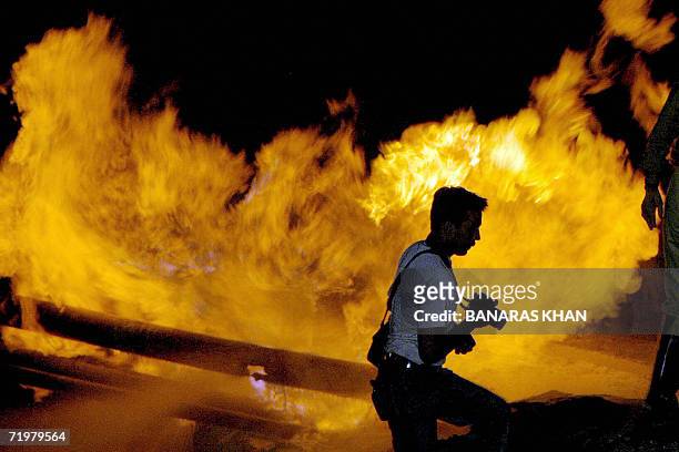 Pakistani photographer walks past the burning gas pipeline near Quetta, late 23 September 2006. Insurgents blew up a natural gas pipeline in the...